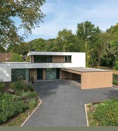 a modern house in the middle of a park with lots of trees and bushes around it