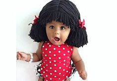 a baby doll with black hair wearing a red polka dot dress