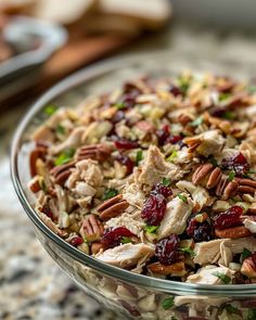 a glass bowl filled with chicken and cranberry salad on top of a table