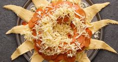 a plate topped with pasta and cheese on top of a black table next to a fork