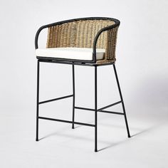 a wicker bar stool with a white cushion on the seat and backrests