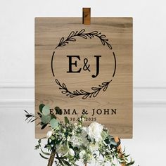 a wooden sign that says e and j on it with flowers in the foreground