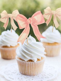 three cupcakes with bows on them sitting on a doily