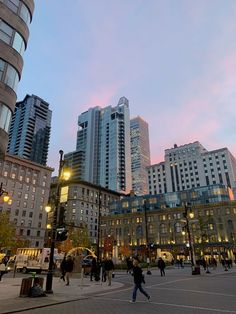 people are walking around in the city at sunset or dawn, with tall buildings behind them