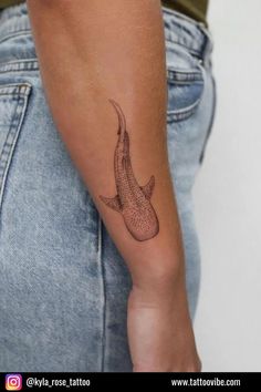 a woman's arm with a tattoo on it that is shaped like a fish