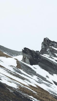 a person on skis going down a snowy mountain side with rocks in the background