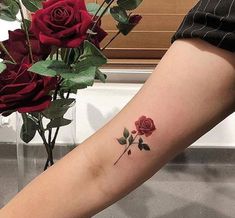 a woman's leg with a rose tattoo on it and flowers in the background