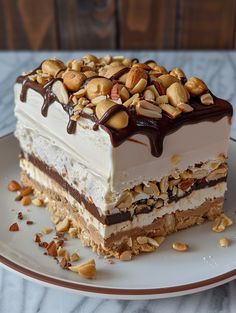 a piece of cake on a plate with nuts and chocolate drizzled over it