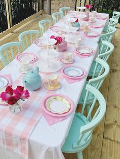 the table is set with pink and blue plates, cups, and teapots