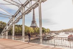 a person standing on a bridge looking at the eiffel tower