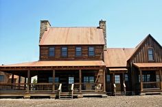 a large wooden house sitting on top of a dirt field