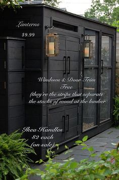 a black shed with the words written on it and some plants in front of it