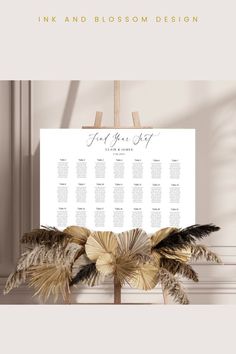 the wedding seating chart is displayed on a easel with feathers in front of it