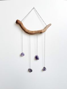 a piece of driftwood hanging on a chain with three amethysts dangling from it