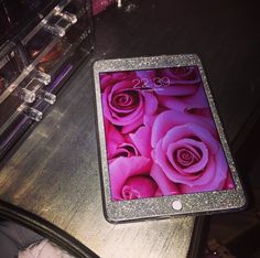 an ipad sitting on top of a wooden table next to pink roses and acrylic