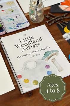 the little woodland artists book sits on a table next to markers and paintbrushes