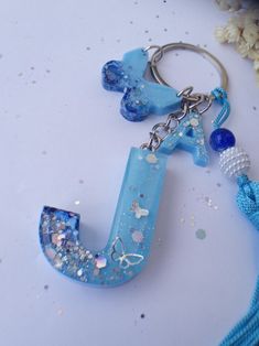 a blue keychain that has a letter j on it and some beads around it