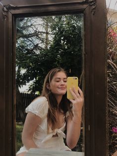 a young woman taking a selfie in front of a mirror with her cell phone