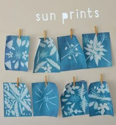 blue and white snowflakes are hung on clothes pins with the words sun prints with kids