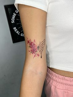 a woman's arm with a tattoo on it that has pink flowers and a humming