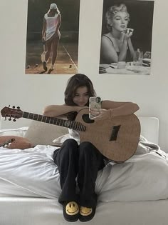 a woman sitting on top of a bed with a guitar in front of her face