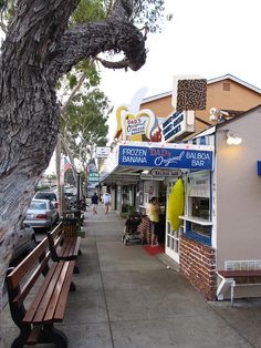 people are walking down the sidewalk in front of a bar and restaurant on a sunny day