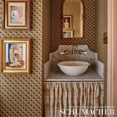 a bathroom with pictures on the wall and a bowl sink in the middle of it