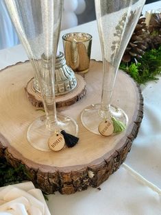 two wine glasses sitting on top of a wooden slice with personalized tags attached to them