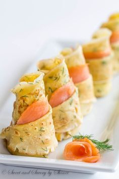 small appetizers are arranged on a white plate with carrots and dill