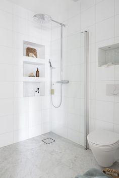 a bathroom with white tile walls and flooring, including a walk - in shower