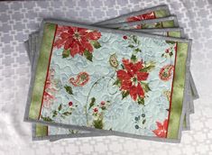 four coasters with floral designs on them sitting on a tablecloth covered surface,