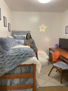 a woman is sitting on her bed holding a dog