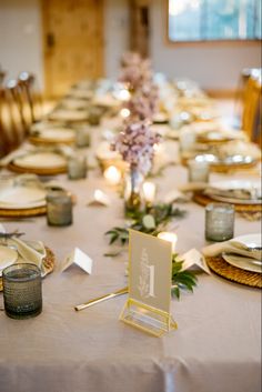 a long table is set with place settings and flowers