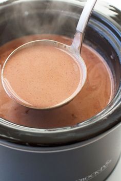 a ladle full of hot sauce being stirred in an electric pressure cooker