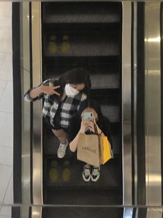 a woman wearing a face mask while riding an escalator with her cell phone