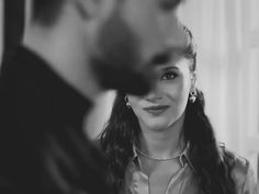 black and white photograph of a woman looking at her reflection in the mirror with another person behind her