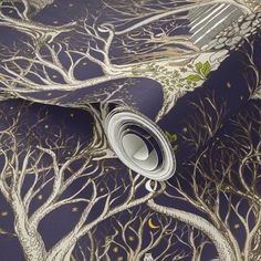 a blue and gold tree wallpaper with white branches on it's side, next to a roll of tape