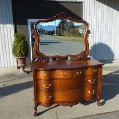 an old dresser with a mirror on the top and drawers below it is outside in front of a building