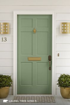 a green front door with two potted plants on the side and numbers above it