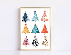 a colorful christmas tree art print in a gold frame on a white wall with polka dots