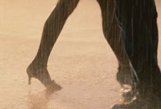 a woman in high heels walking through the rain