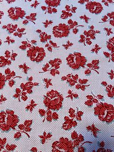 red flowers on white fabric with polka dots and holes in the center, closeup