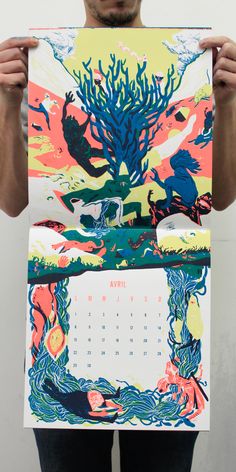 a man is holding up a calendar with an image of a tree and sea creatures on it