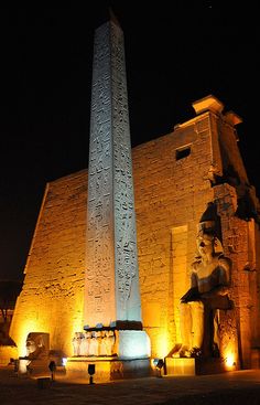 the obelisk is lit up at night in front of an egyptian style building