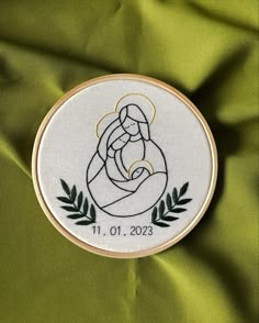 a cross stitched onto a green cloth with the image of a mother holding her child