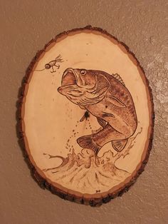 a wooden plaque with a fish on it's side and a fishing hook in the middle