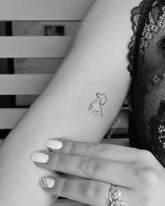 a woman's arm with a small dog tattoo on the left side of her arm