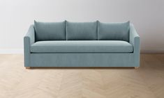 a blue couch sitting on top of a hard wood floor next to a white wall