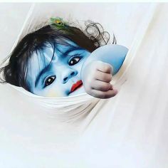 a young child with blue paint on his face is peeking out from behind a white curtain