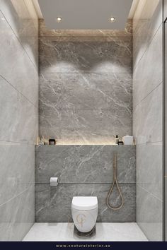 a modern bathroom with grey marble walls and flooring, along with a white toilet